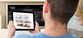 Junger Mann sitzt mit Tablet auf Couch